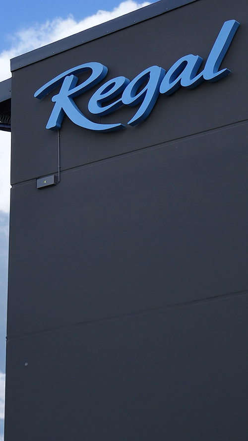 Blue Regal sign on dark building, blue sky and clouds.